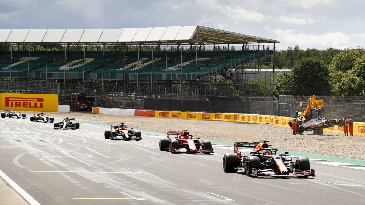 Piloti projíždějí kolem nabouraného vozu Kevina Magnussena v závodě v Silverstone
